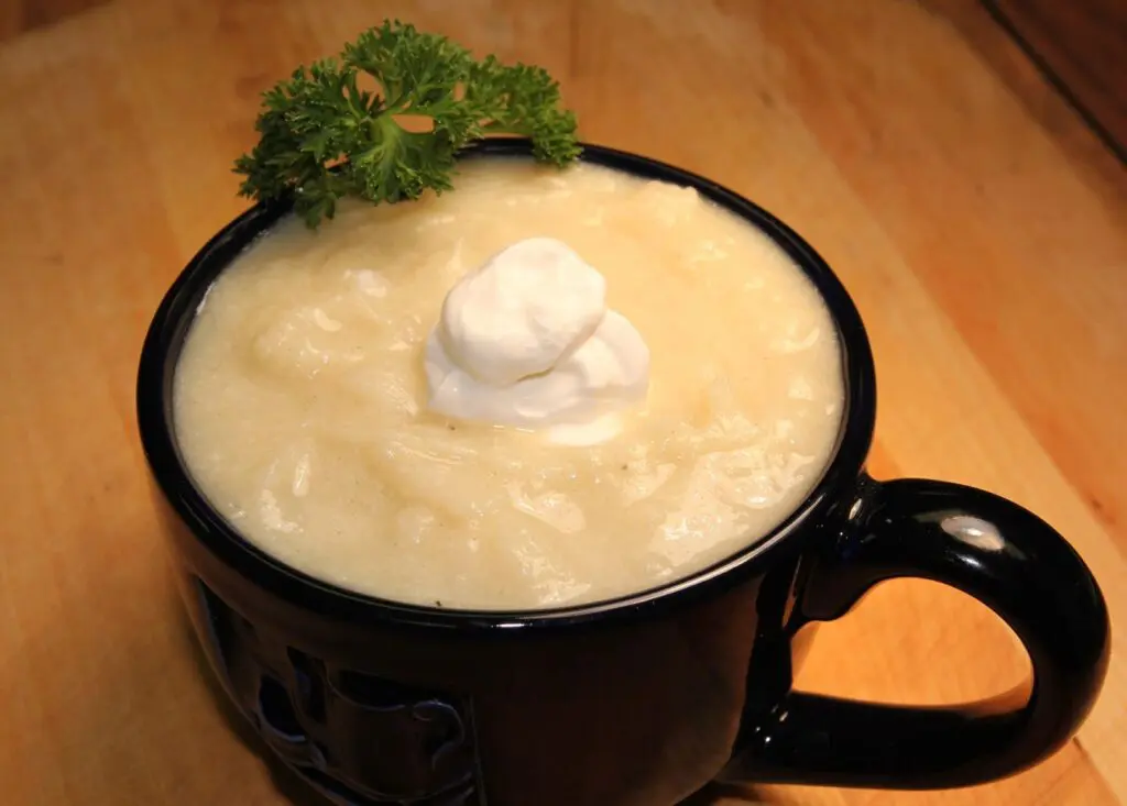 Creamy potato soup served in a black mug with a parsley garnish.
